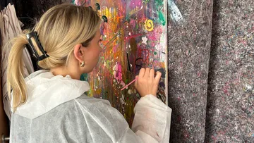 Frau malt buntes abstraktes Kunstwerk im Studio.