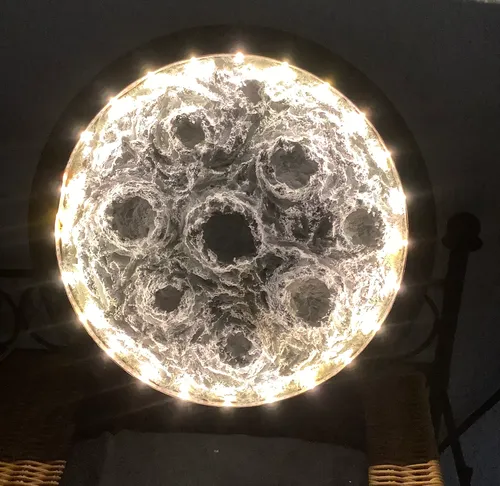 Circular lamp with intricate pattern, glowing softly.