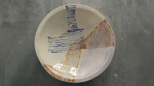 Ceramic plate with abstract lines on table.