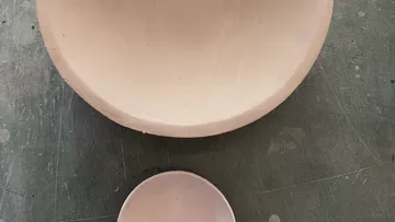 Zwei Ton-Schalen auf einer texturierten Fläche.