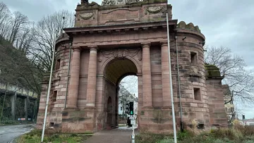 Historic archway in urban park setting.
