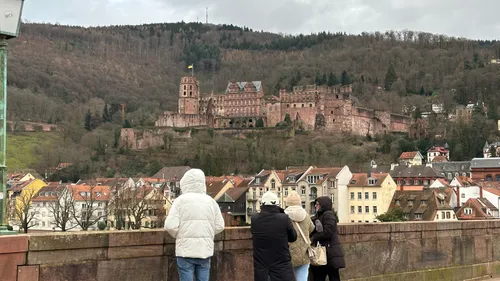 Tourists photographing Heidelberg Castle on cloudy day.