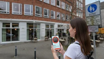 Woman using phone outside urban cafe.