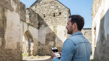 Mann nutzt Smartphone in historischen Ruinen.