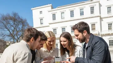 Group looking at phone outside building.