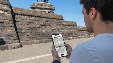 Person using phone near historic monument.