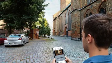 Man using phone near brick church.