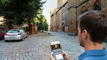 Man using smartphone in cobblestone street.