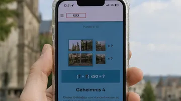 Hand hält Handy mit Quizanzeige im Freien.