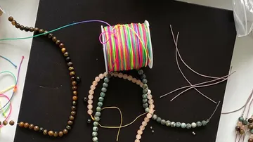 Beads and colorful cords on black surface.