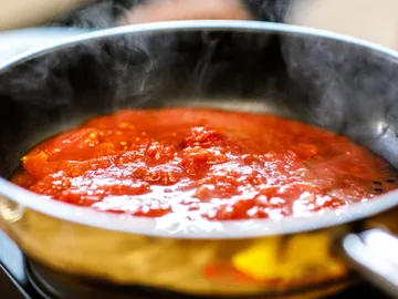 Tomato sauce is cooked in a pan on the stove.