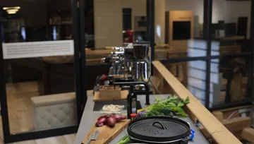 Kitchen counter with vegetables, cutting board, kitchen tools.