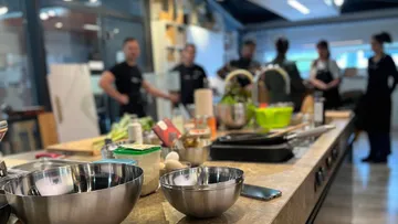 Bowls on kitchen counter, chefs in background.