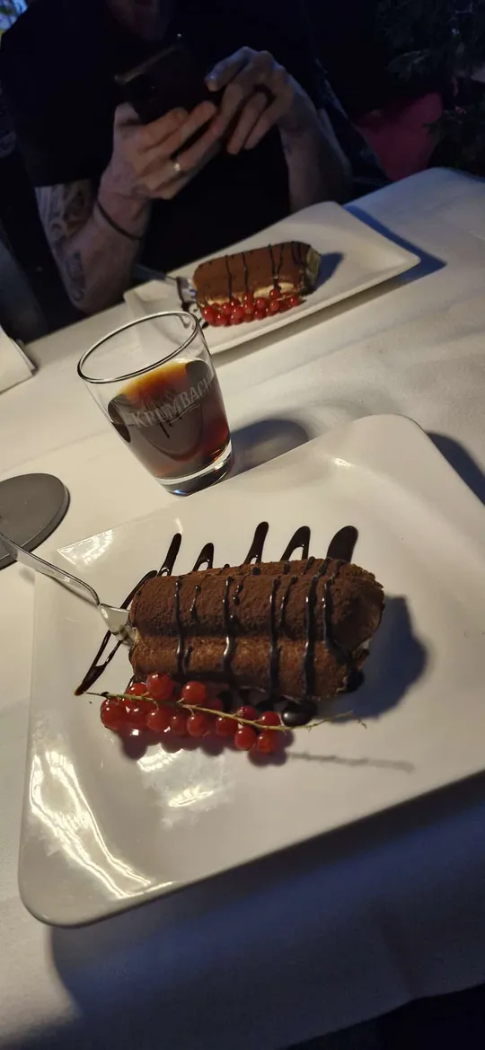 Schokoladendessert mit Beeren und Getränk auf Tisch.