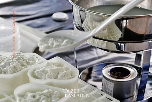 Cheese curds scooped into molds, kitchen setting.