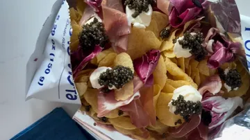 Kaviar, Chips, Schinken auf einem Tablett.