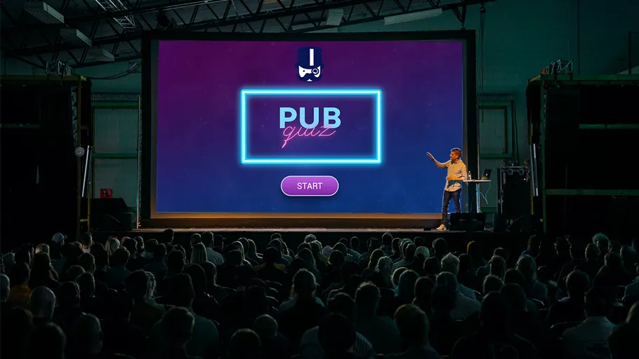 Person präsentiert Quiz im Auditorium auf Großbildschirm.