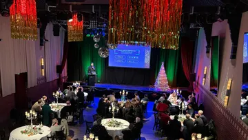 Speaker presents at festive dinner event.