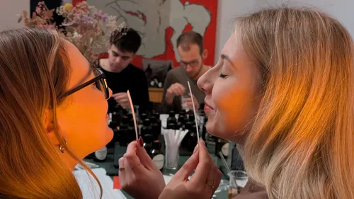 Two women smell scent strips, others in background.