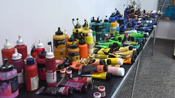 Bottles and tubes of paint on table.
