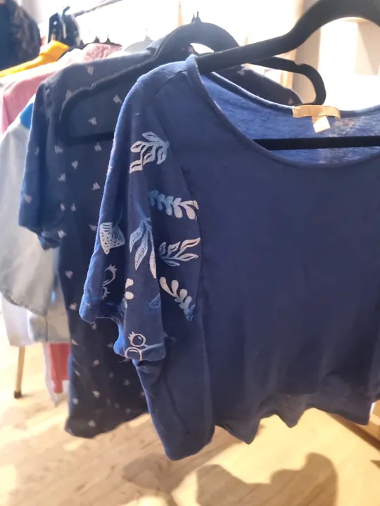 Blue shirts hanging on clothing rack.