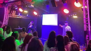 Performers sing on stage to an audience.