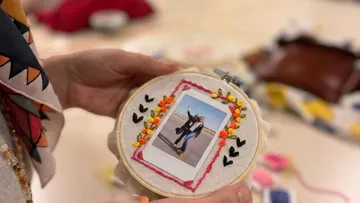 Hand holds embroidery hoop with photo inside.