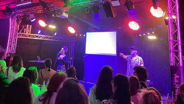 Performers sing on stage with crowd watching.