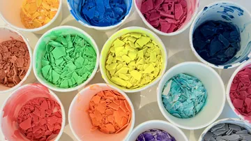 Bunte Wachsspäne in weißen Bechern.