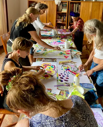 Adults painting at a table indoors.