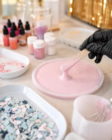 Hand mischt rosa Flüssigkeit auf Basteltisch.