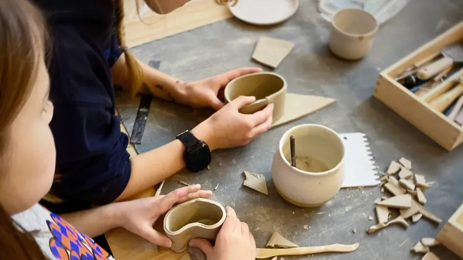 People crafting pottery at a table.