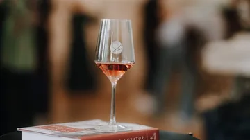 Weinglas mit Roséwein auf einem Buch.