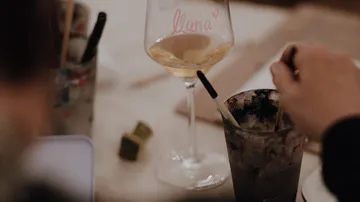 Hand stirring glass on a cluttered table.