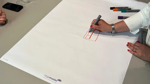 Hand zeichnet auf großem Papier mit Markern.