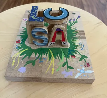 Painted wooden letters on floral board.