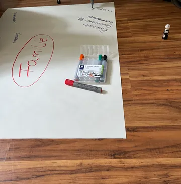 Markers and paper on wooden floor.