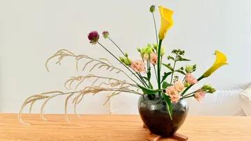 Blumengesteck in Vase auf Holztisch.