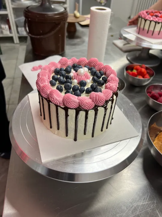 Cake decorated with berries and pink frosting.