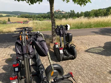 Segways parken an Landstraße, Bäume in der Nähe.