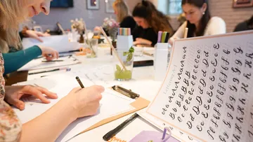 Menschen üben Kalligraphie in einem Workshop.