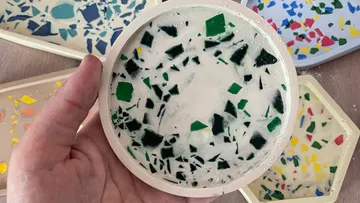 Hand holding terrazzo-style coaster with colorful patterns.