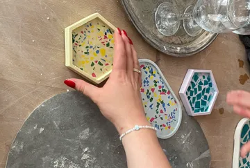 Hand arranging colorful terrazzo coasters on table.