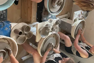 People crafting pottery on wheels indoors.