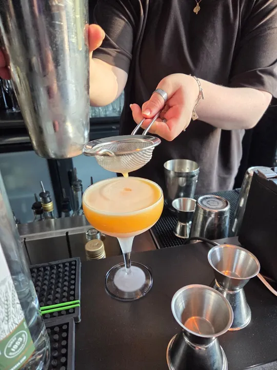Barkeeper siebt Cocktail an der Theke ab.