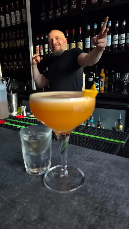 Cocktail auf der Theke, Barkeeper posiert dahinter.