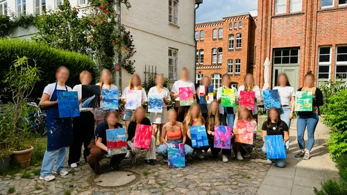 Group showing paintings in courtyard outdoors.