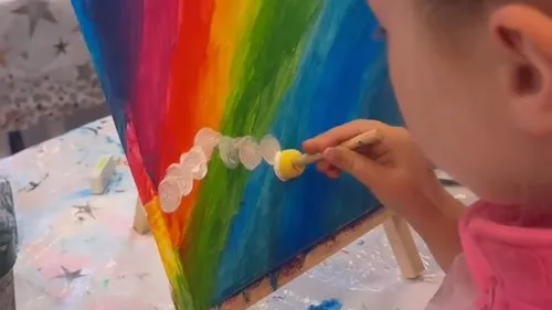 Child painting colorful canvas with brush.