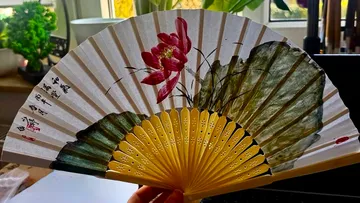 Dekorativer Fächer mit Blumendesign drinnen.