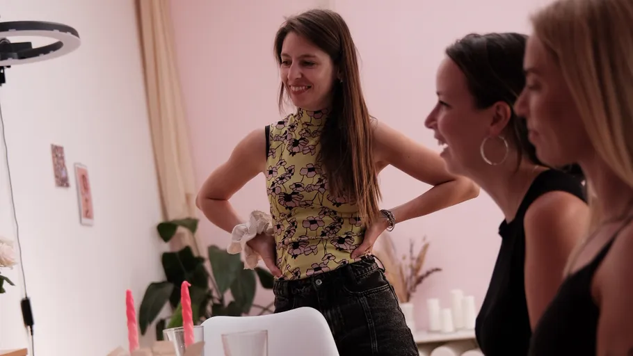 Frauen lächeln, versammelt um einen Tisch drinnen.